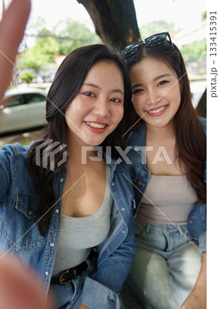 Capturing Memories. Two friends taking a selfie with a smartphone in a park. Capturing Memories. Two friends taking a selfie with a smartphone in a park. 133415391