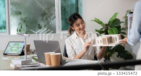 Sustainable Design. Businesswoman showcasing a model of an eco-friendly building. Sustainable Design. Businesswoman showcasing a model of an eco-friendly building. 133415472