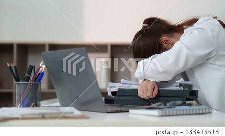 Exhausted office worker resting head on desk due to stress Exhausted office worker resting head on desk due to stress 133415513