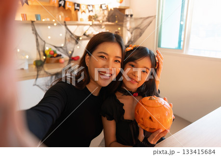 Halloween Moments. Smiling mother and daughter posing with a pumpkin. Halloween Moments. Smiling mother and daughter posing with a pumpkin. 133415684