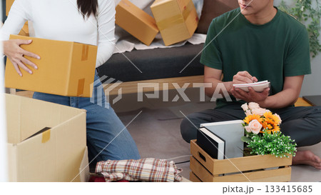 Couple Collaborating to Unpack Boxes in Cozy Living Room Couple Collaborating to Unpack Boxes in Cozy Living Room 133415685
