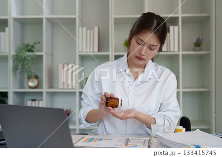 Young woman managing medication intake in office 133415745