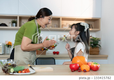 Healthy Eating. Mother engaging daughter with colorful salad in modern kitchen. Healthy Eating. Mother engaging daughter with colorful salad in modern kitchen. 133415782