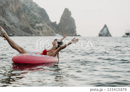 Woman, floating, sea. Happy woman on inflatable donut in the sea near cliffs on a summer vacation with copy space. 133415879
