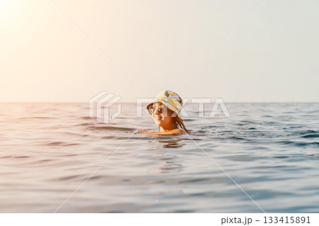 Woman Swimming Sea Hat Summer - A woman in a hat is swimming in the sea on a summer day. Woman Swimming Sea Hat Summer - A woman in a hat is swimming in the sea on a summer day. 133415891