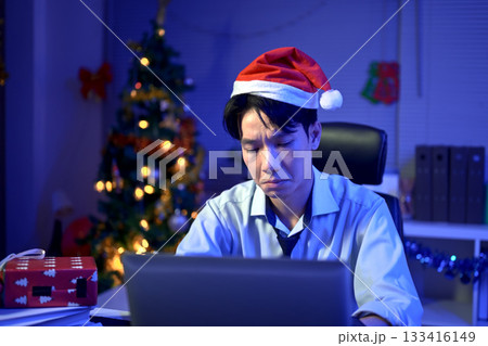 Bored, Christmas hat and portrait of a tired man in the office with a laptop, exhausted and young businessman with xmas decorations in the modern workplace. 133416149