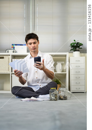 Stressed young man holding so many expenses bills in his hand no money to pay debt 133416156