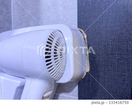 Wall-mounted white hair dryer in bathroom 133416750