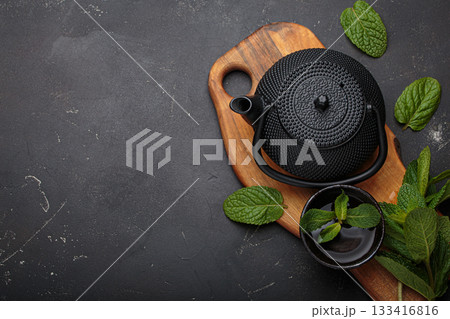 Cast iron black teapot cup herbal mint tea relax wellness healthy detox copy space Cast iron black teapot cup herbal mint tea relax wellness healthy detox copy space 133416816