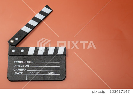 Clapperboard on an orange background, representing filmmaking and the start of a movie. 133417147