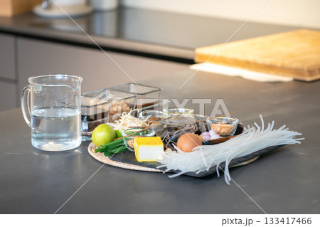 fresh Ingredient of PadThai, Famous Thai Menu stir fried noodle with shrimp, local herb, and sauce are arranged in studio light on gray granite top kitchen counter. 133417466