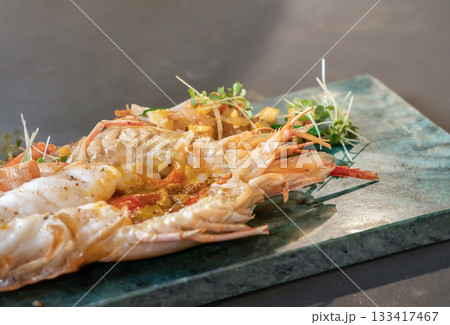 Close up to the Lobster Pad Thai is ready to serve with fried noodle, tofu and other ingredients on a rectangular plate in studio light. Close up to the Lobster Pad Thai is ready to serve with fried noodle, tofu and other ingredients on a rectangular plate in studio light. 133417467