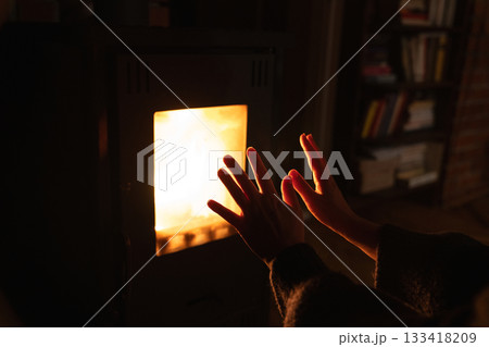 Close up of hands close to oven with glass window and fire inside. 133418209