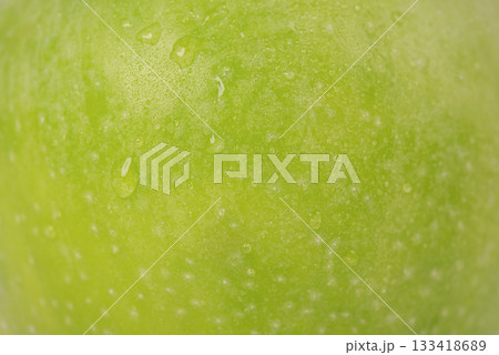 Green apple with drops as a background macro photo. Green apple skin. Green apple with drops as a background macro photo. Green apple skin. 133418689