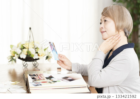 孫や子供の写真をアルバムに入れるシニア女性 孫や子供の写真をアルバムに入れるシニア女性 133421592
