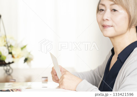 孫や子供の写真をアルバムに入れるシニア女性 133421596