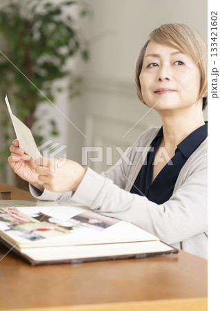孫や子供の写真をアルバムに入れるシニア女性 133421602