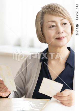 孫や子供の写真をアルバムに入れるシニア女性 133421613