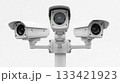 Three white security cameras mounted on a pole are observing the surroundings. This modern electronic surveillance system provides constant public safety and digital protection outdoors. 133421923
