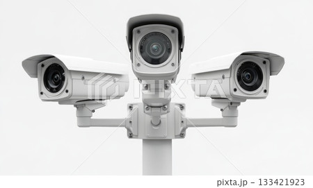 Three white security cameras mounted on a pole are observing the surroundings. This modern electronic surveillance system provides constant public safety and digital protection outdoors. 133421923