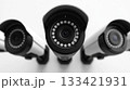 Group of modern security cameras mounted on a pristine white wall, featuring advanced electronic eyes providing vigilant digital observation and reliable indoor protection. 133421931