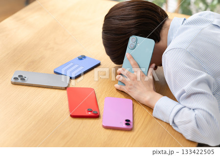 スマホを見ながら電話をする女性 133422505