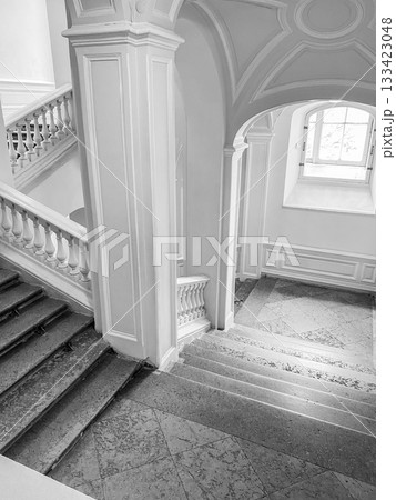 A beautifully designed interior featuring a staircase with white railings and polished marble flooring. Sunlight illuminates the airy space. A beautifully designed interior featuring a staircase with white railings and polished marble flooring. Sunlight illuminates the airy space. 133423048