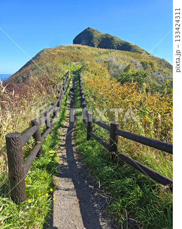 A wooden fence lines the path, inviting exploration of the natural landscape and offering stunning views 133424311