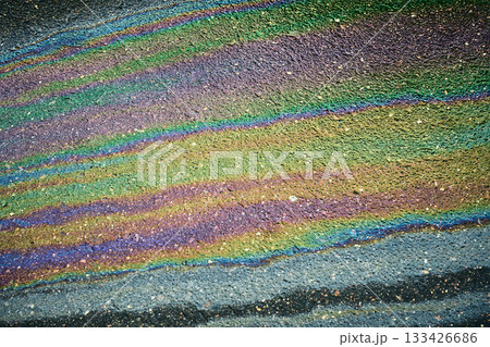 Oil slick spreads rainbow colors and iridescent texture across dark asphalt Oil slick spreads rainbow colors and iridescent texture across dark asphalt 133426686