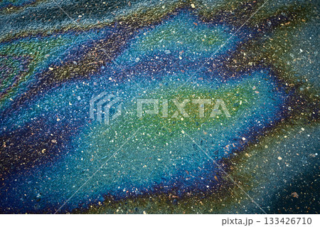 Oil slick on asphalt creating colorful iridescent patterns, symbolizing pollution and environmental impact Oil slick on asphalt creating colorful iridescent patterns, symbolizing pollution and environmental impact 133426710