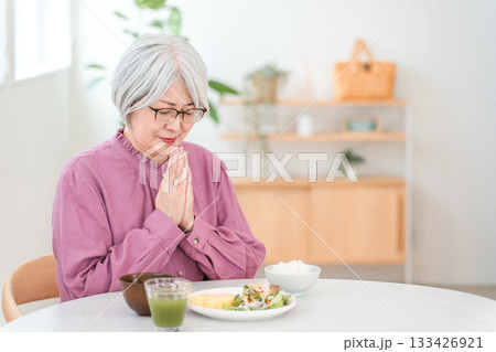 自宅のダイニングで食事をするグレイヘアーのシニア女性 133426921