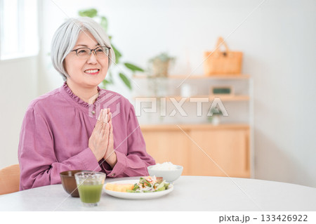 自宅のダイニングで食事をするグレイヘアーのシニア女性 自宅のダイニングで食事をするグレイヘアーのシニア女性 133426922