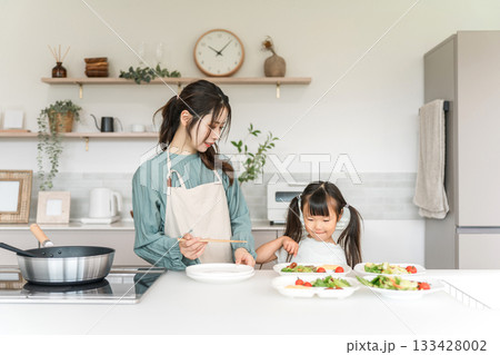 キッチンで料理をするママのお手伝いをする子供、娘 キッチンで料理をするママのお手伝いをする子供、娘 133428002