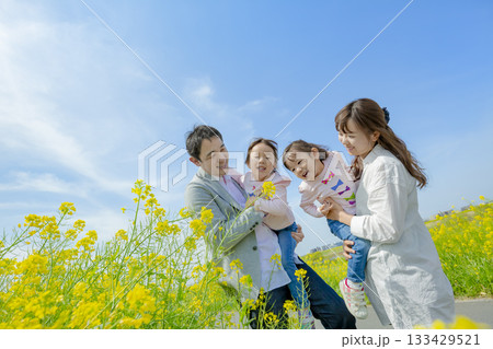 菜の花の咲く遊歩道で遊ぶ4人家族 133429521