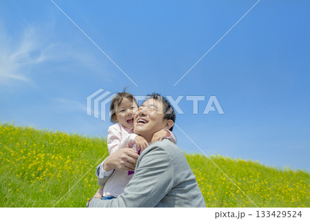 菜の花の咲く遊歩道で遊ぶ父親と娘 133429524