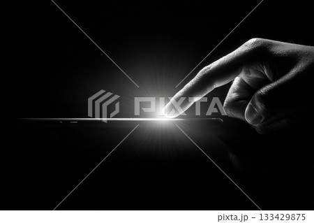 Minimalist Black-and-White Image of Hand Touching Glowing Smartphone Minimalist Black-and-White Image of Hand Touching Glowing Smartphone 133429875