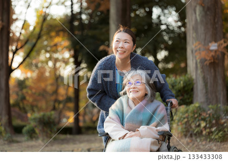 秋の綺麗な紅葉で車椅子で散歩する高齢者の女性と介護士や娘のような人 秋の綺麗な紅葉で車椅子で散歩する高齢者の女性と介護士や娘のような人 133433308