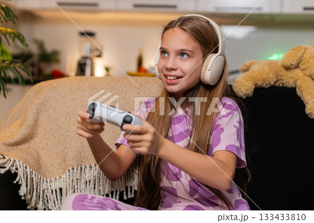 Teenager girl holds game controller plays console game intense focus emotion enjoys evening time fun Teenager girl holds game controller plays console game intense focus emotion enjoys evening time fun 133433810