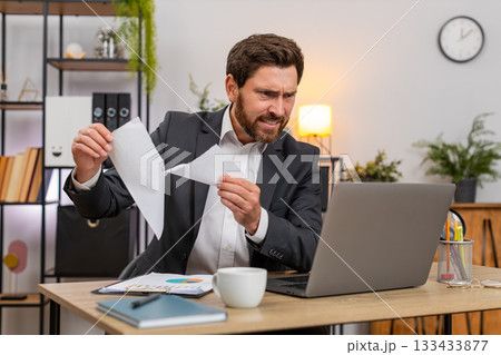 Middle-aged businessman rips draft after error opens new document and types fast on laptop with zeal 133433877