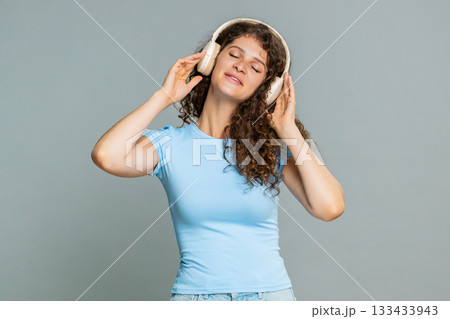 Woman happily putting headphones dancing smiling enjoying favorite song cheerful music reaction 133433943