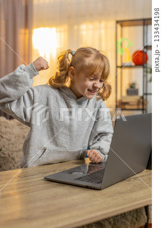 Young girl frustrated after losing game on laptop, expressing disappointment with upset reaction 133434198