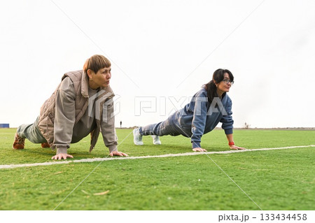 Two Russian women, aged 50 and 60, perform a classic plank pose at a stadium. 133434458