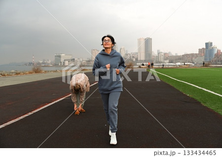 Two Russian women, aged 50 and 60, in tracksuits, run around a stadium in Vladivostok. Two Russian women, aged 50 and 60, in tracksuits, run around a stadium in Vladivostok. 133434465