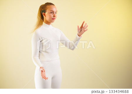 Woman in smartglasses gesturing against yellow background Woman in smartglasses gesturing against yellow background 133434688