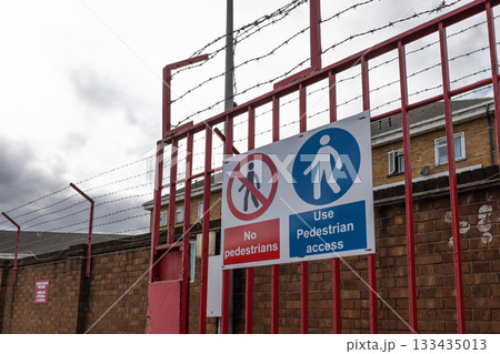 Industrial security gate with barbed wire and no entry safety signs 133435013