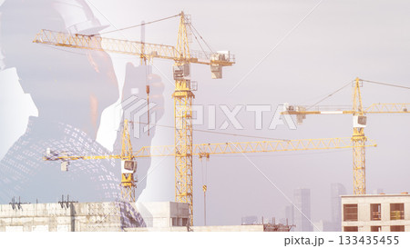 A construction worker in safety gear is seen giving instructions on a walkie-talkie against a backdrop of a construction site with construction cranes. They are responsible for organizing the 133435455