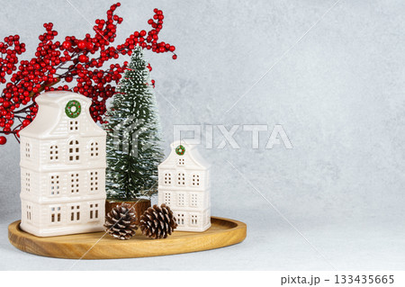Ceramic Christmas houses with pine Tree and winter decorations on wooden tray on white background 133435665