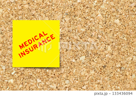 Yellow note paper with word medical insurance on cork board background with copy space 133436094