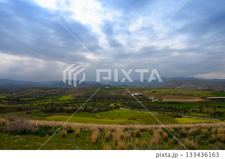 Rolling hills adorned with vibrant greens and dramatic skies in an enchanting countryside landscape 133436163