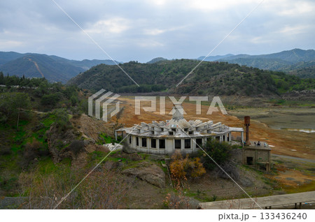 Abandoned structure overlooking dry lakebed with dramatic mountains in the background during overcast afternoon Abandoned structure overlooking dry lakebed with dramatic mountains in the background during overcast afternoon 133436240